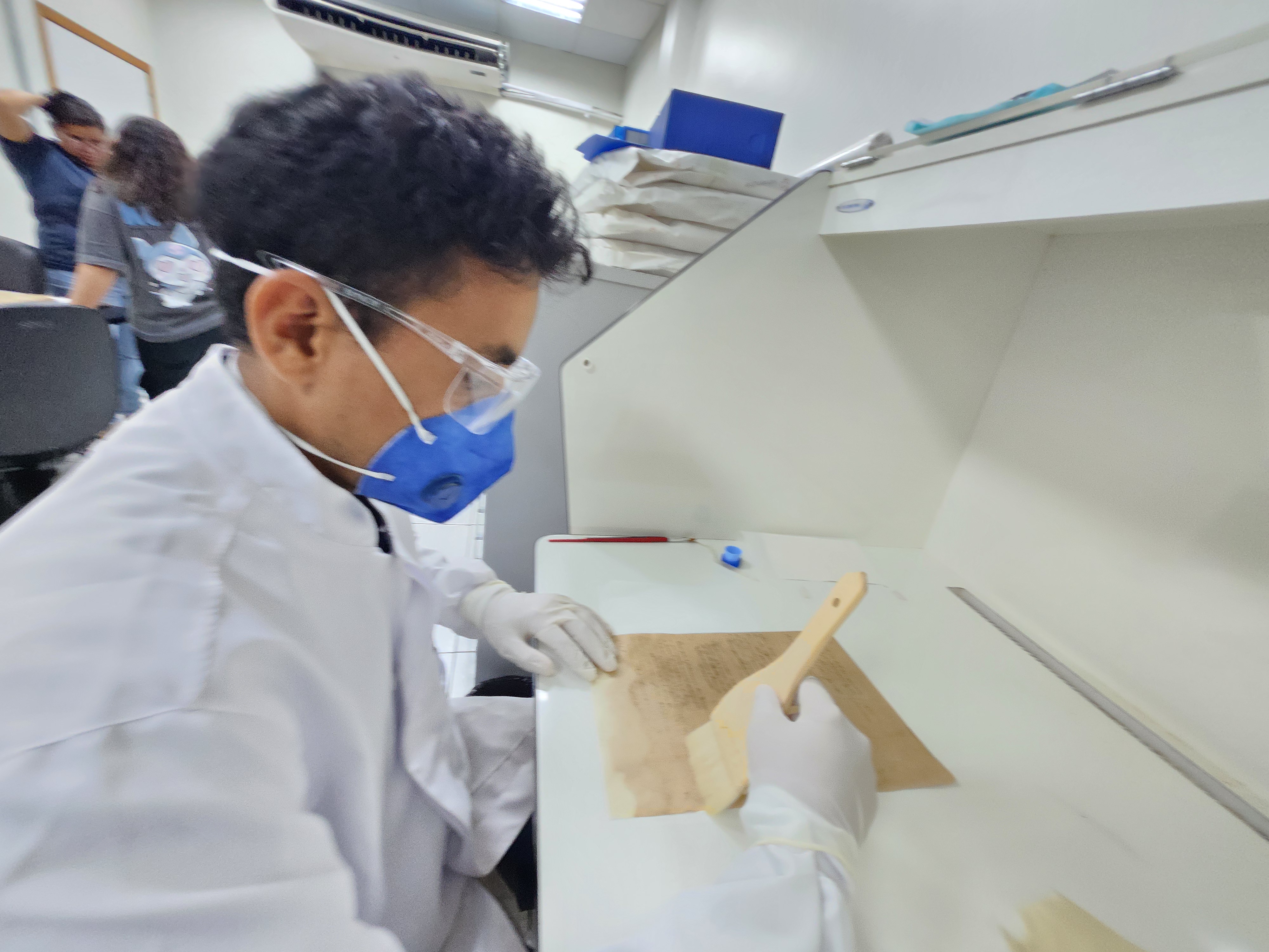 Foto mostra servidor do Arquivo Central do TJAM durante serviço em documento histórico