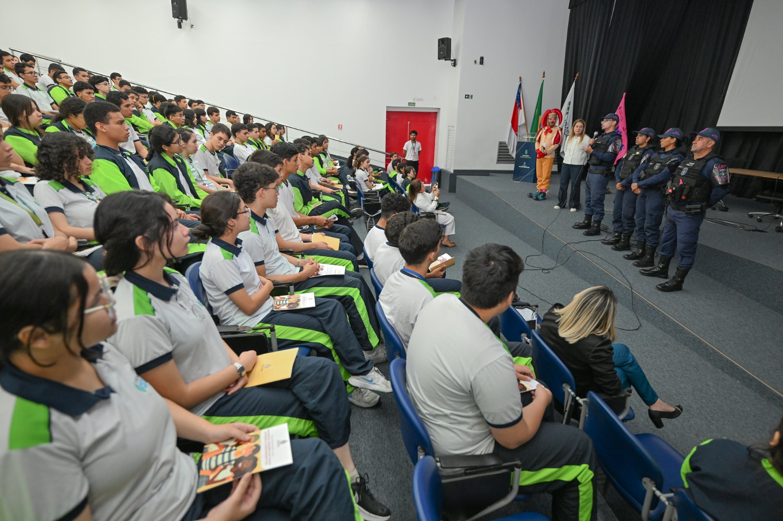 Foto mostra alunos sentados acompanhando um evento