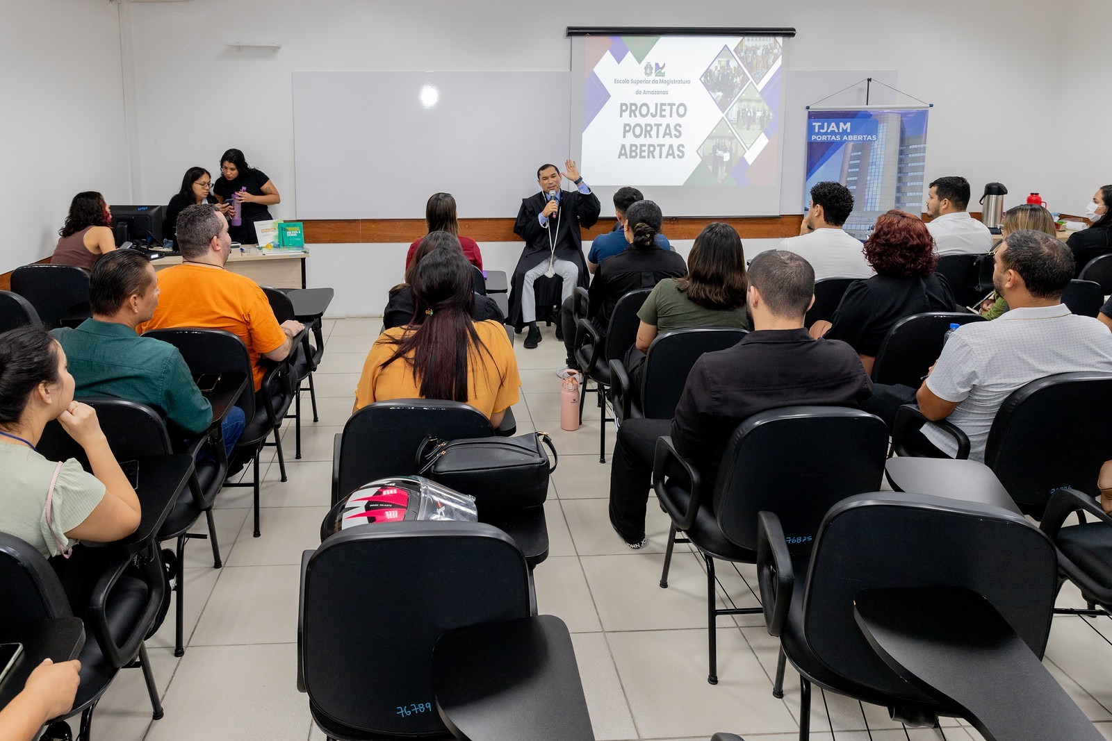 Imagem mostra, ao centro, o juiz Marcelo Cruz falando ao público durante o projeto Portas Abertas