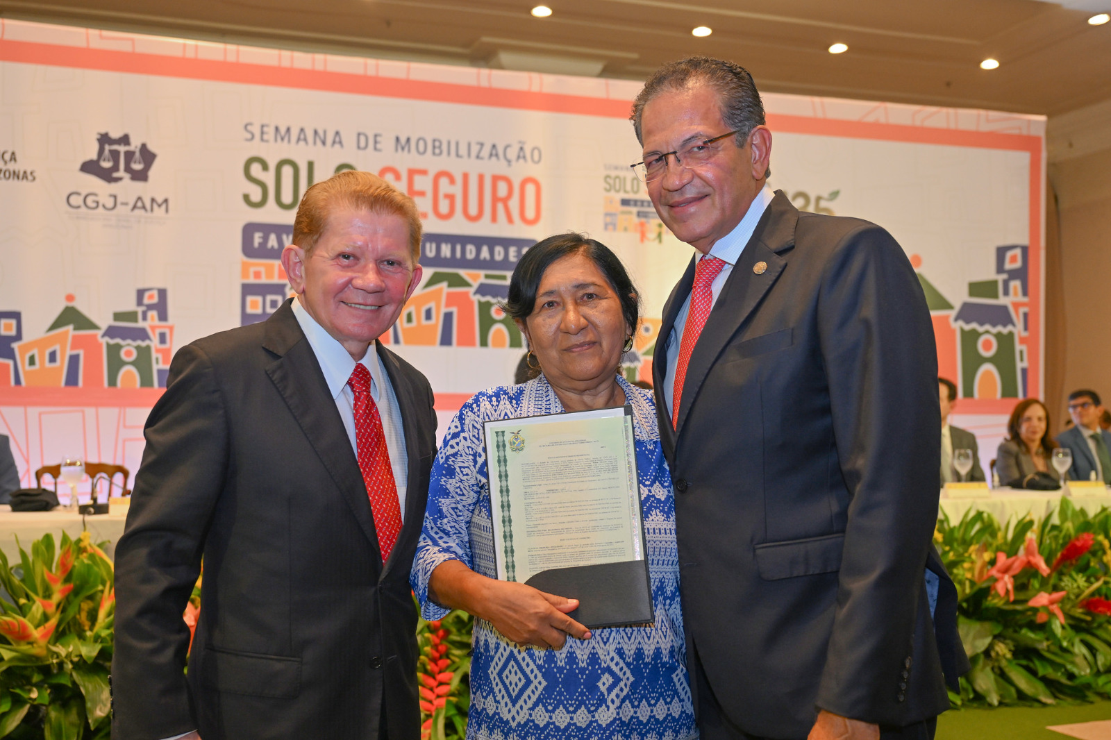 Na foto, o corregedor nacional de Justiça, ministro Mauro Campbell; o corregedor-geral de Justiça, desembargador José Hamilton Saraiva e, ao centro, uma senhora, beneficiada com o título de regularização fundiária