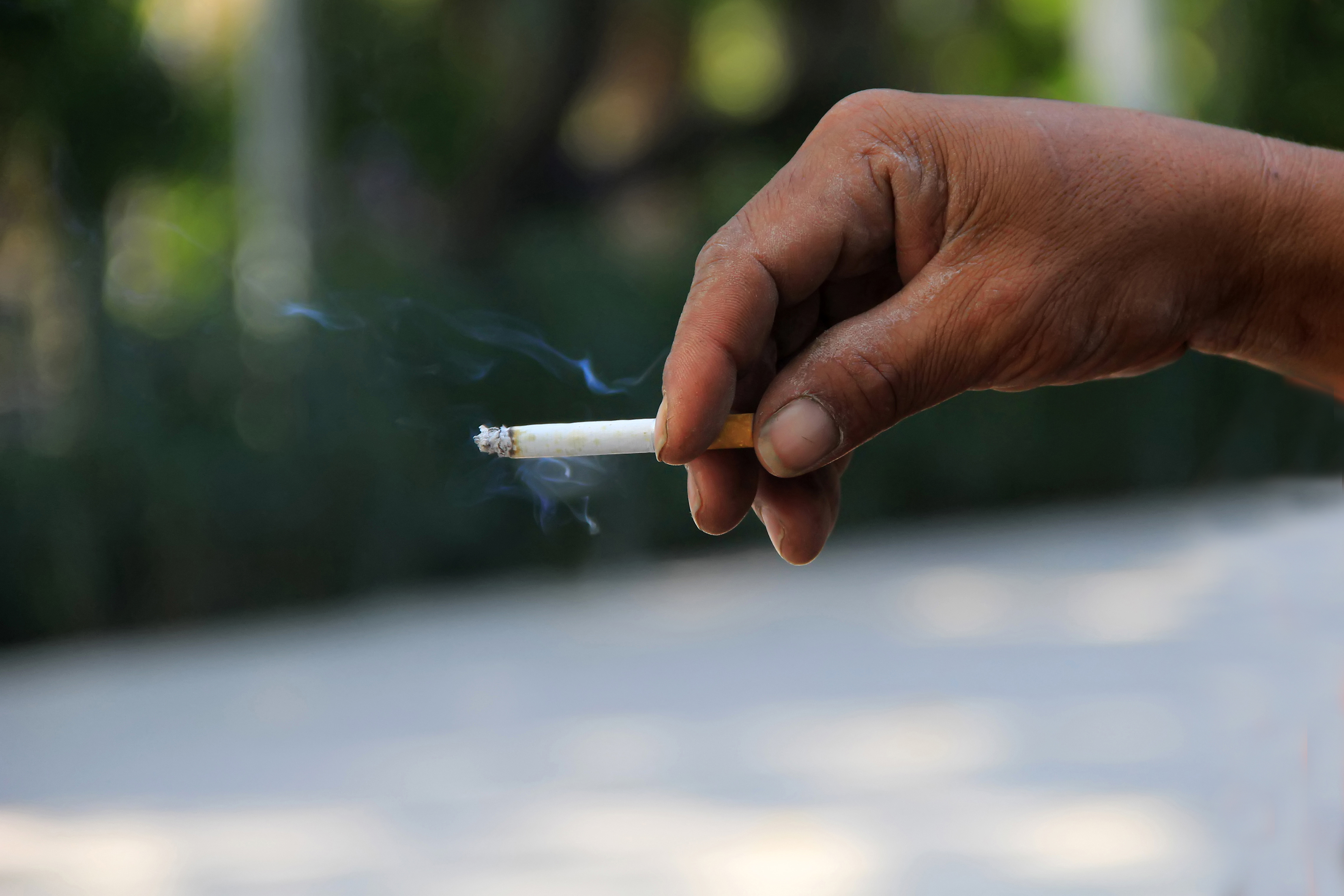man s hand holds cigarette that is burning 1